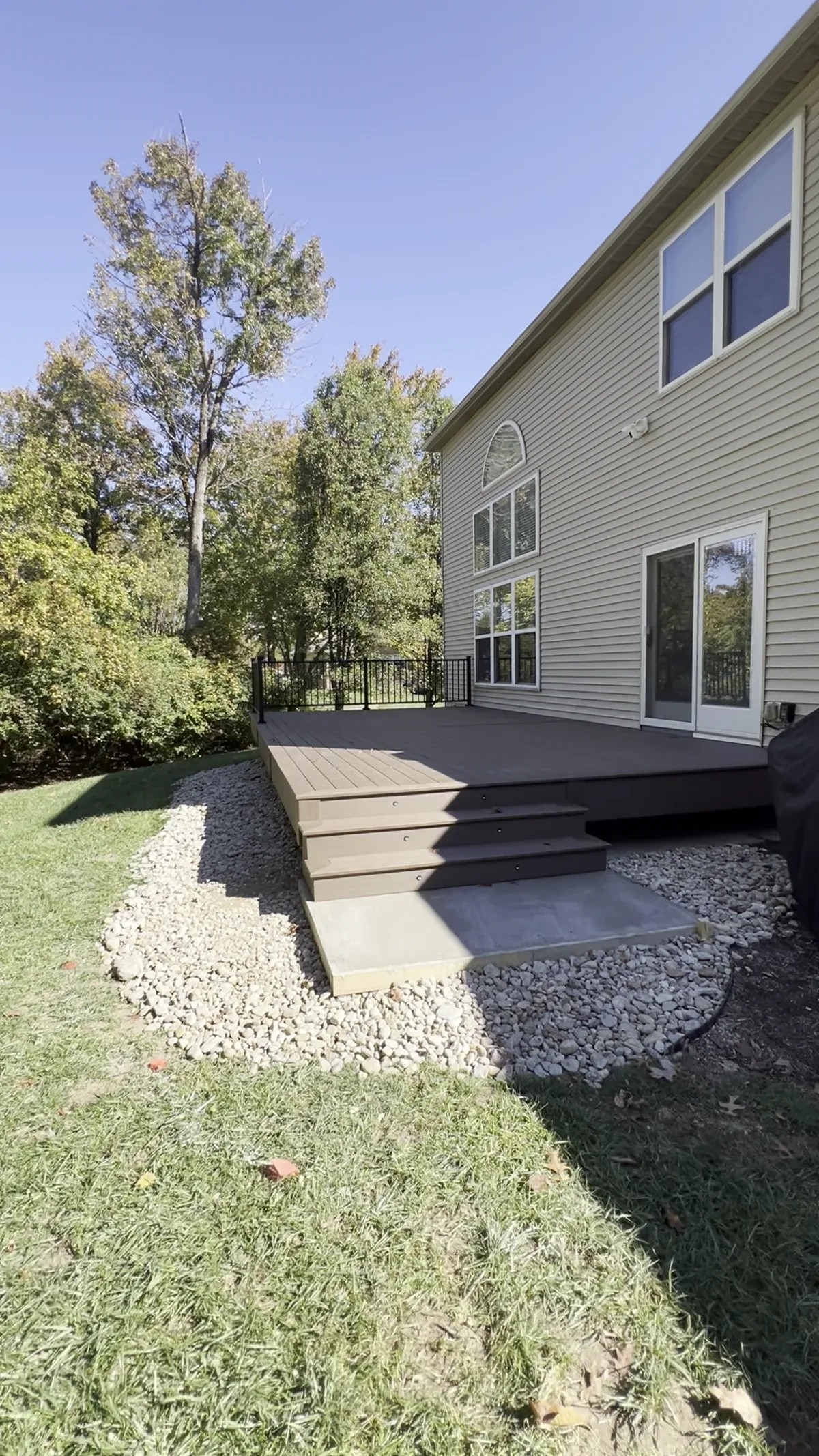 The same deck finished in dark composite with wide steps and black railing
