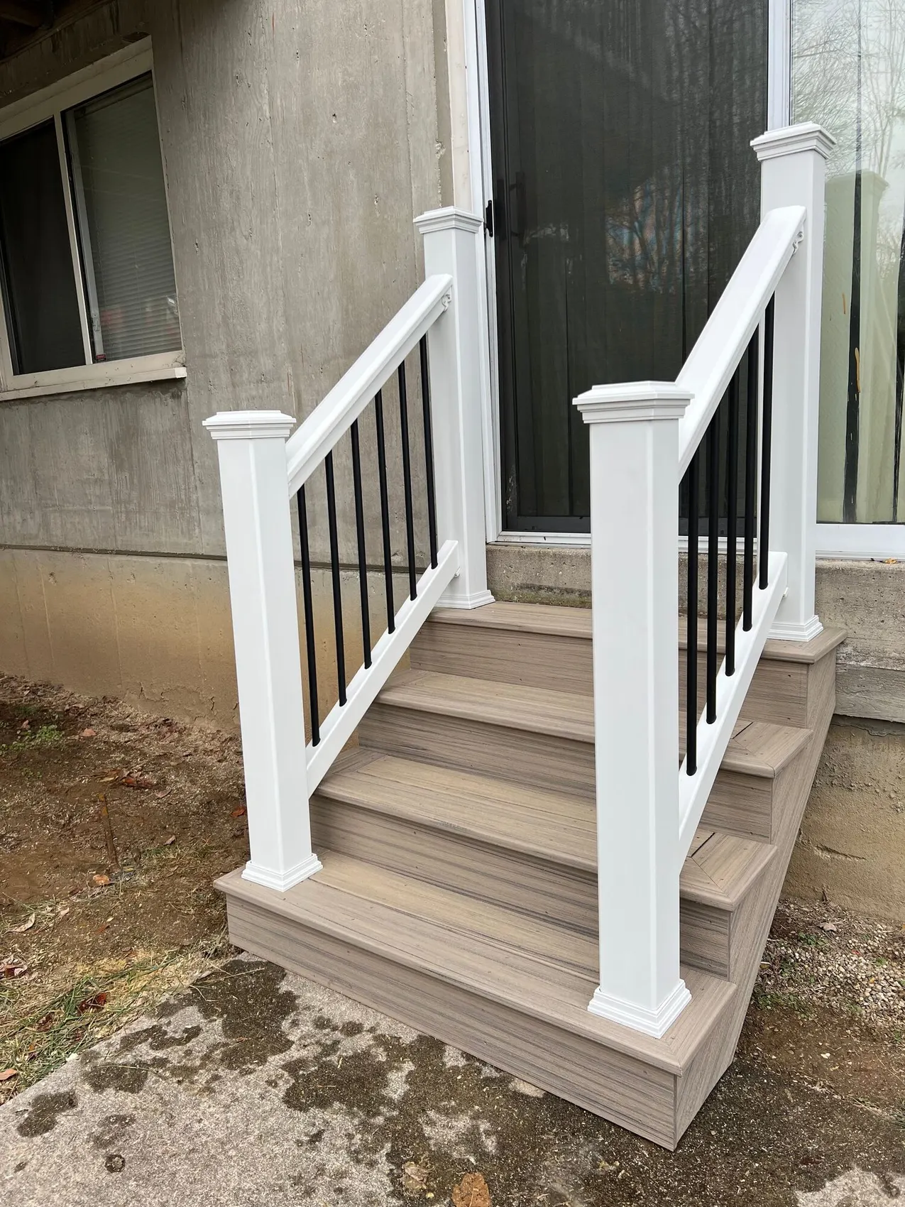 Composite entry steps with white posts at the front of a home