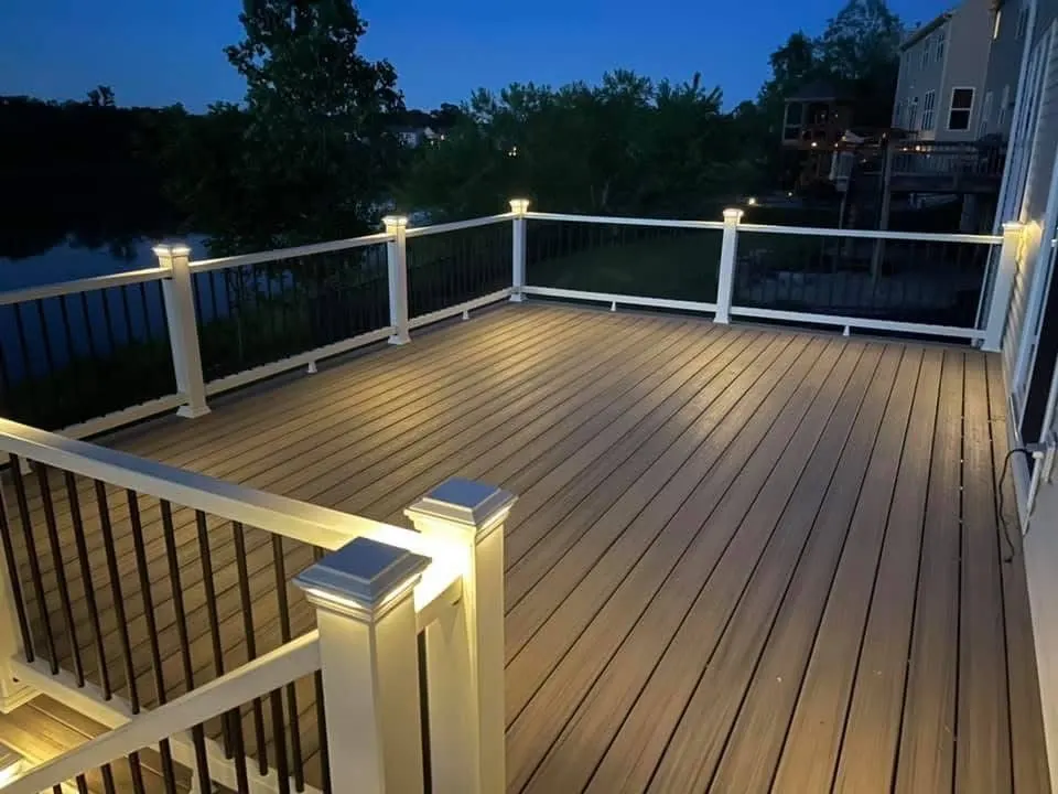 Composite deck at dusk with lit post caps and white railing overlooking water