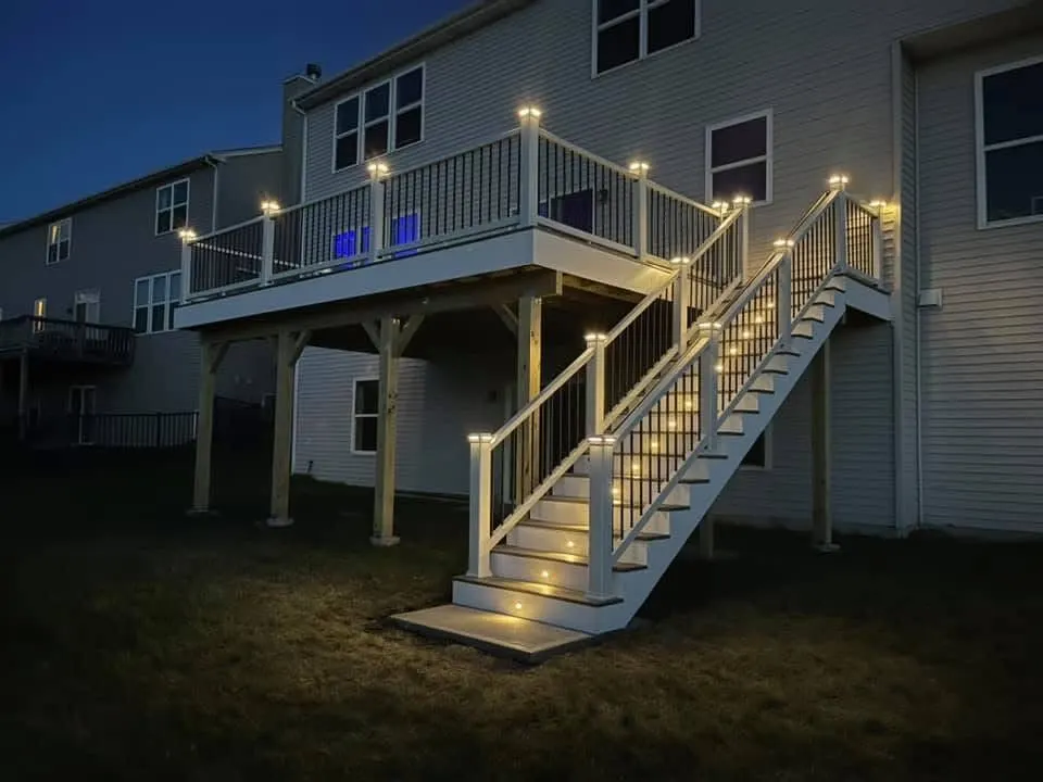 Elevated composite deck lit at night above the yard