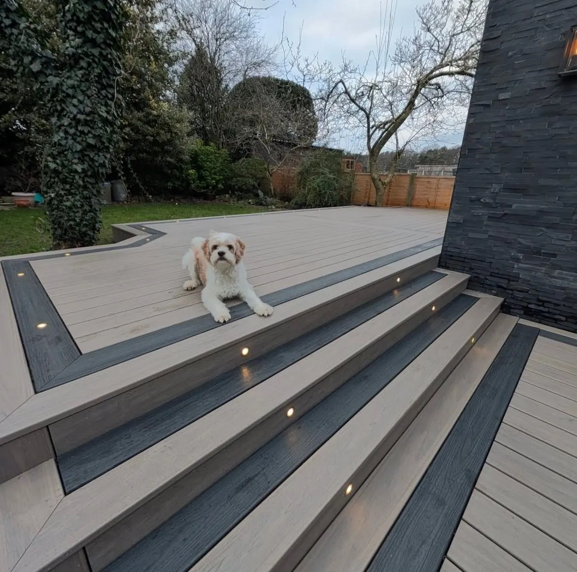 Wide composite steps with lighting set into each riser leading down from a deck